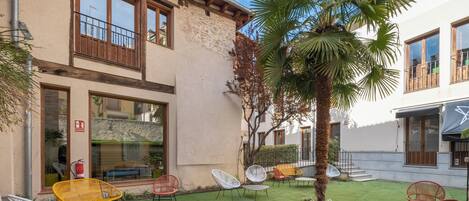 Un patio con mobiliario exterior, una palmera y un edificio con balcones.