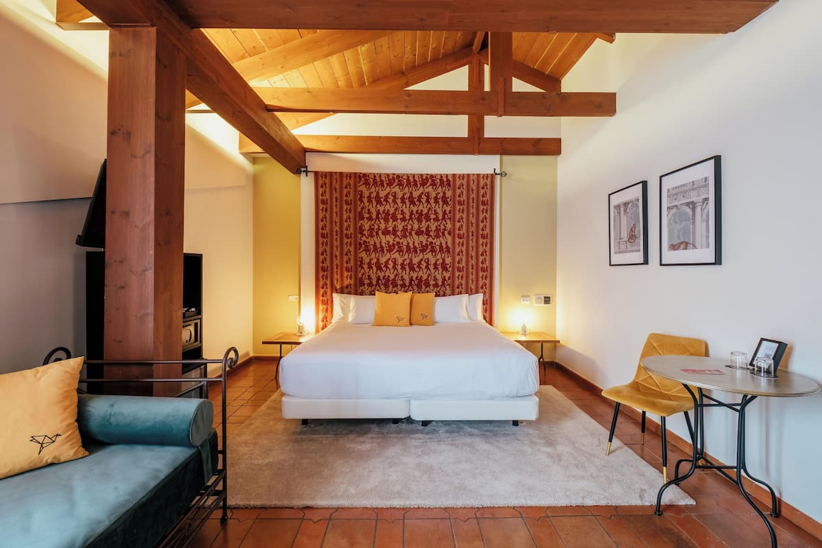 Ein Schlafzimmer mit einem großen Bett, einer Couch, einem kleinen Tisch und einem Sessel.