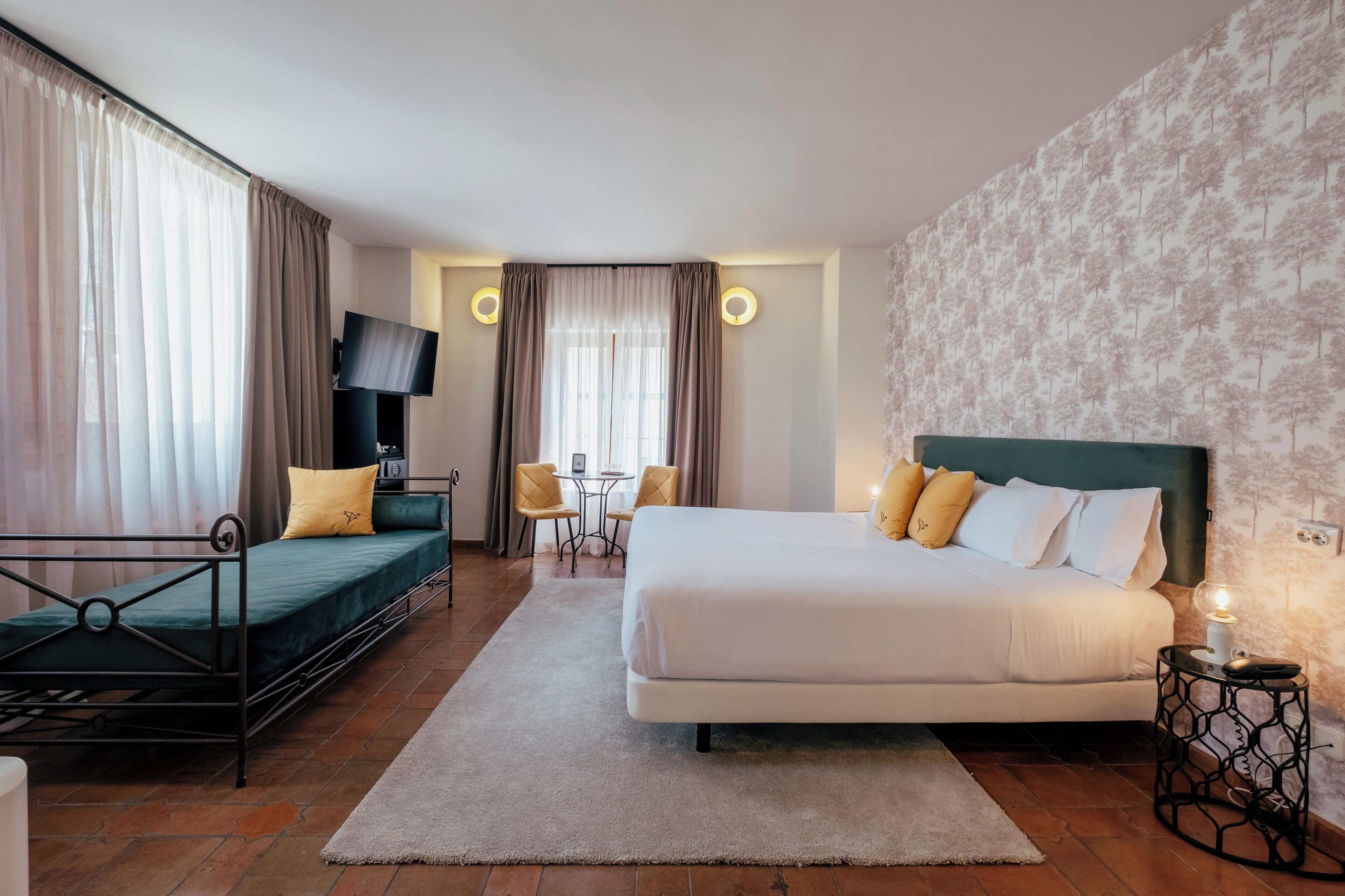 Een hotelkamer met een bed, een slaapbank, een televisie, een bureau en een stoel.
