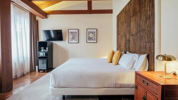 A bedroom with a large bed, a TV, framed pictures, and a wooden headboard.