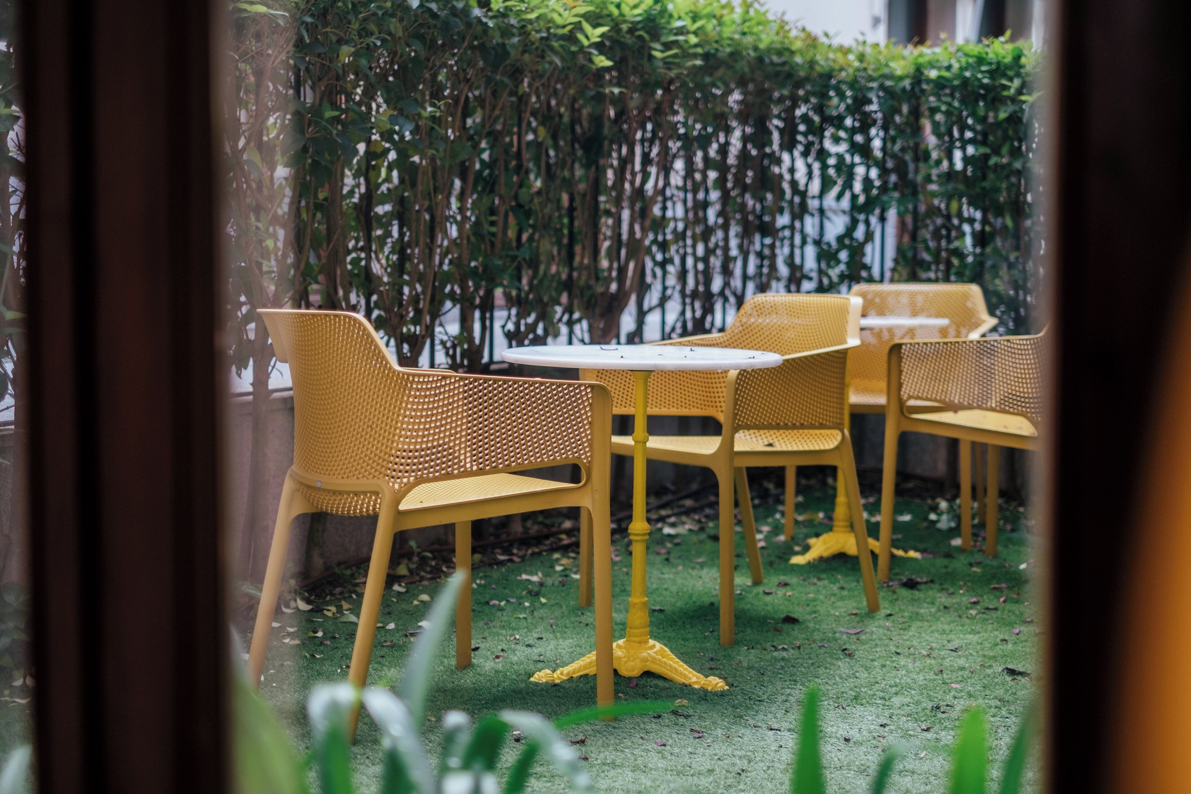 A patio area with yellow wicker furniture and a green artificial turf floor.