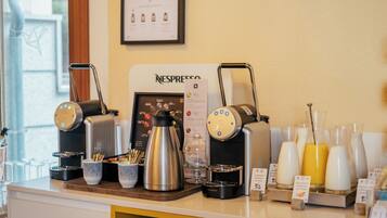A coffee station with a Nespresso machine, coffee pots, milk dispensers, and a variety of coffee cups and mugs.