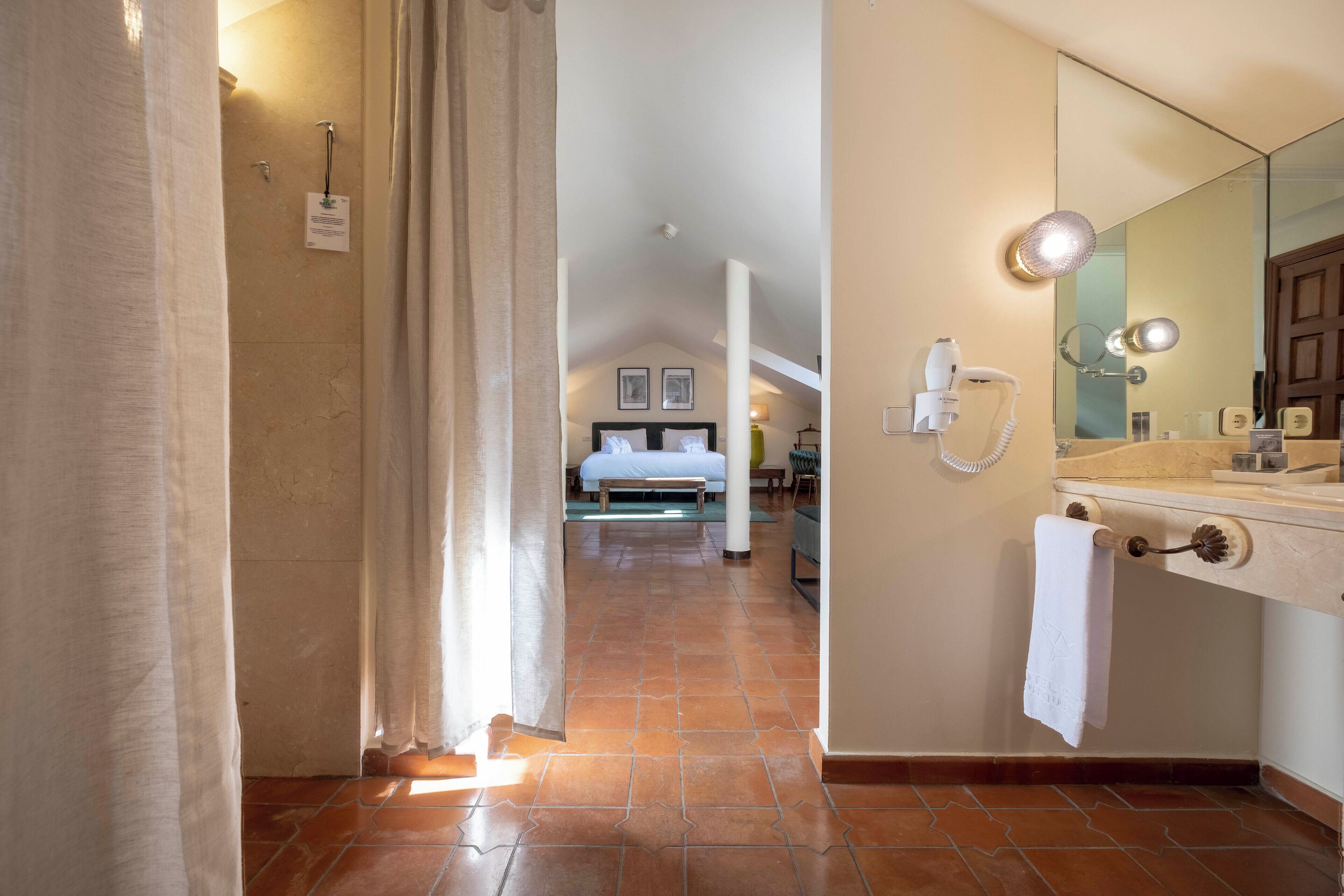 Ein Hotelzimmer mit Bad, Bett, Spiegel und Duschbereich.