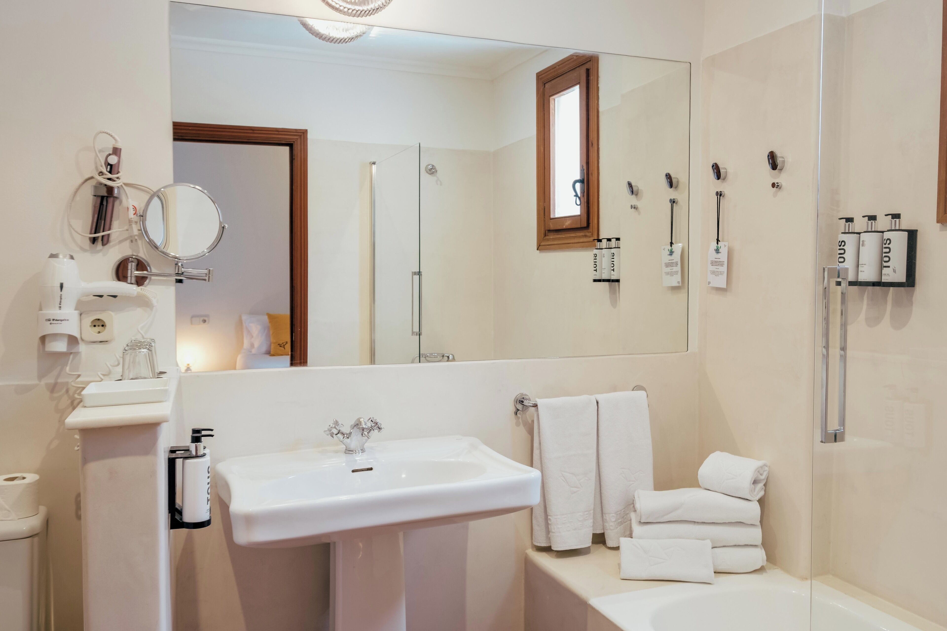 Un baño moderno con un espejo grande, un lavamanos y una ducha con mampara de vidrio.