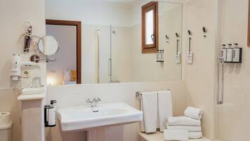 Un baño moderno con un espejo grande, un lavamanos y una ducha con mampara de vidrio.