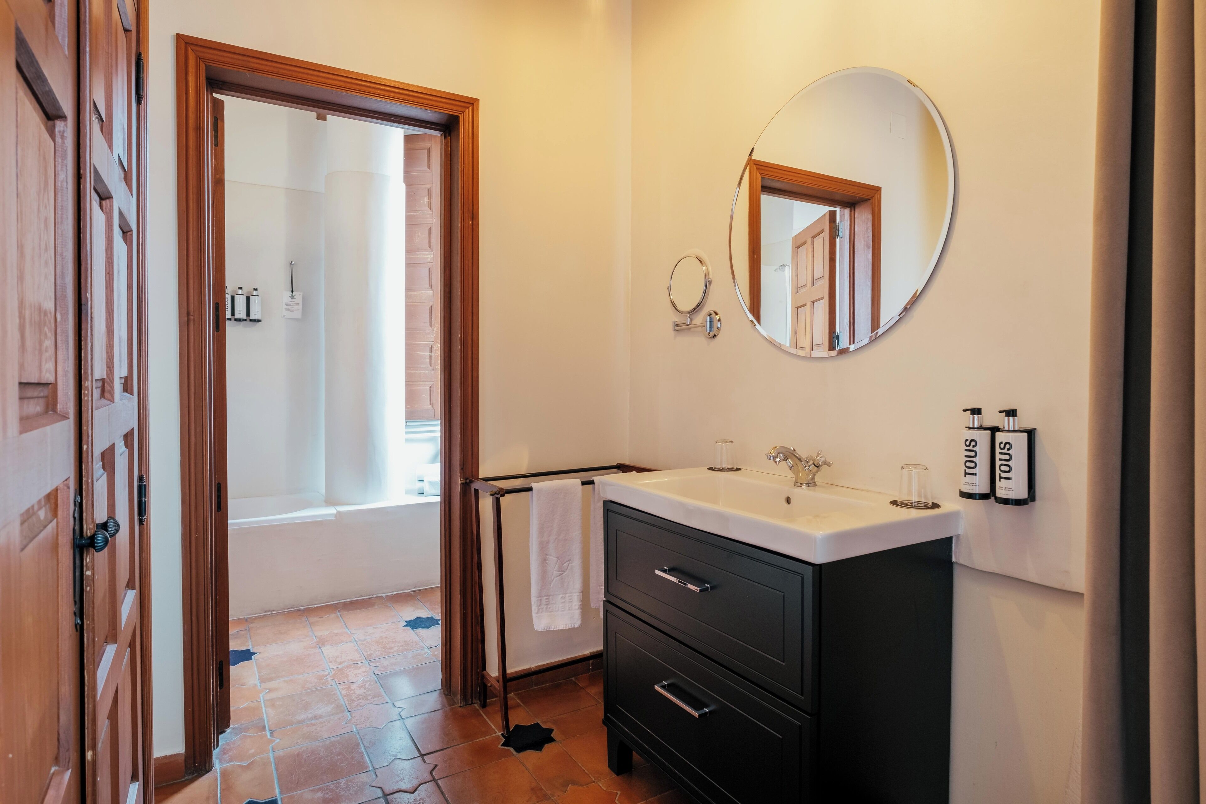 A bathroom with a bathtub, a sink, a mirror, and toiletries on the wall.