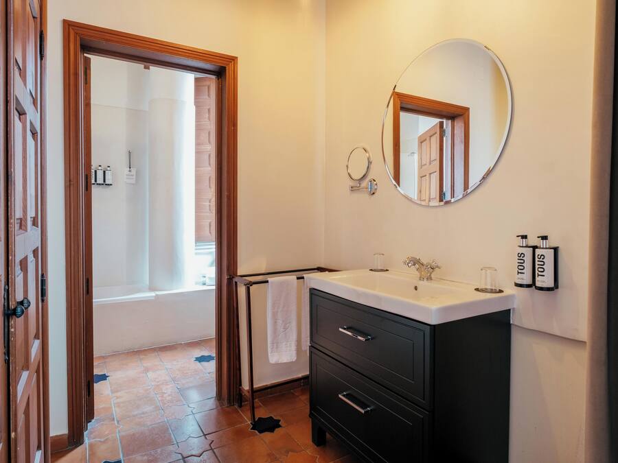 A bathroom with a bathtub, a sink, a mirror, and toiletries on the wall.