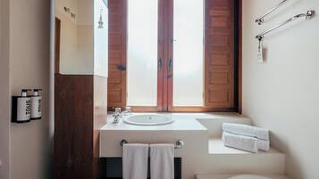 A bathroom with a wooden door, a white sink, a towel rack, and a window with frosted glass.