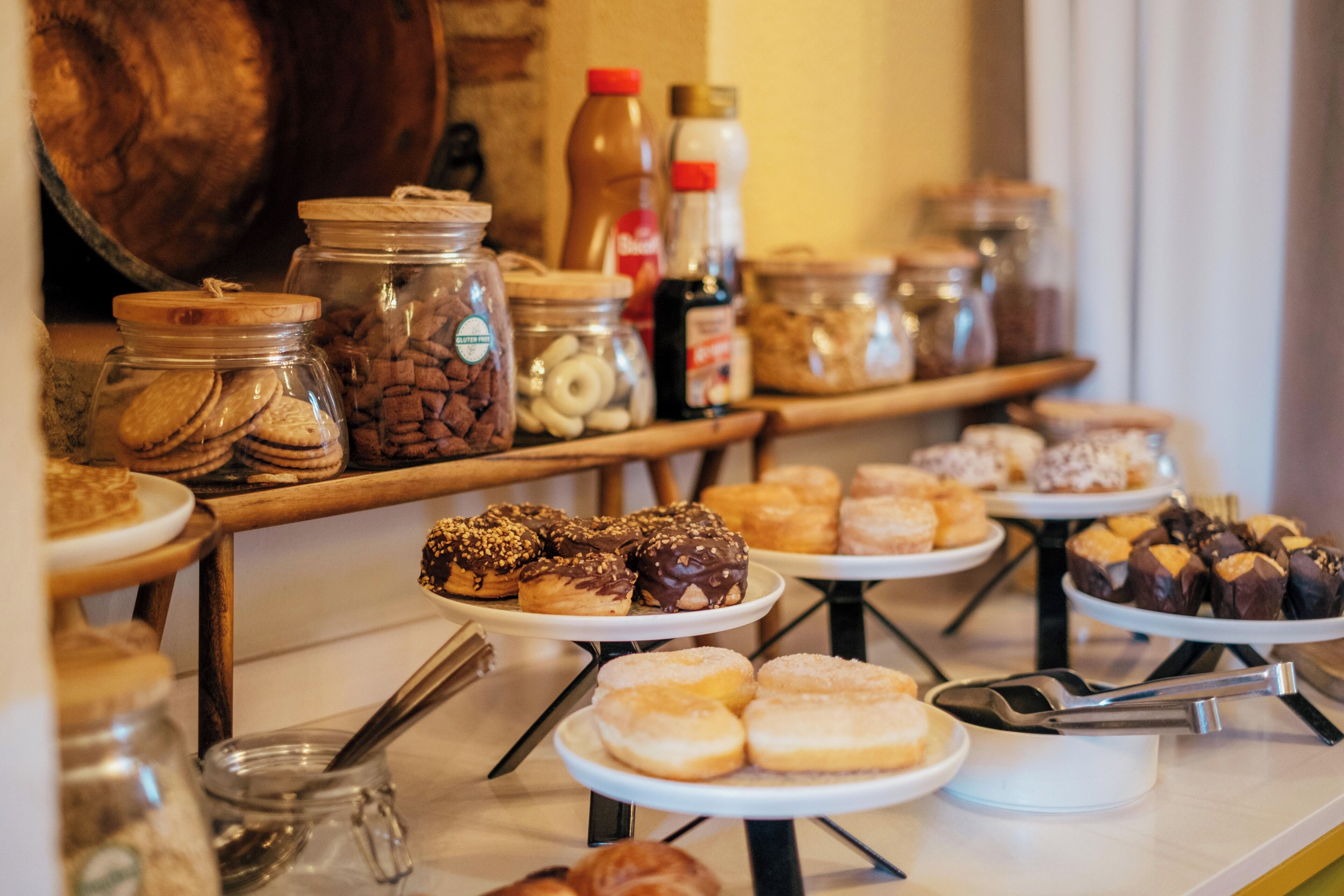 A buffet with various pastries and baked goods, including donuts and cookies, displayed on multiple serving platters.