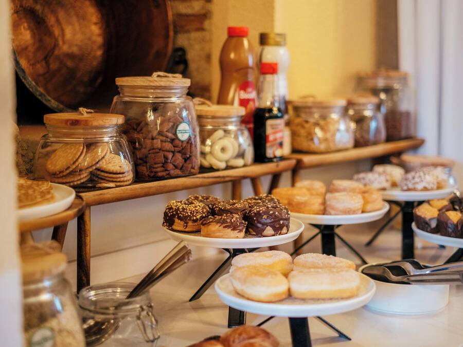 A buffet with various pastries and baked goods, including donuts and cookies, displayed on multiple serving platters.