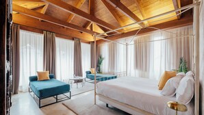 A spacious bedroom with a large bed, a sofa, and a small table. - Hotel Cetina Palacio Ayala Berganza. (Segovia)