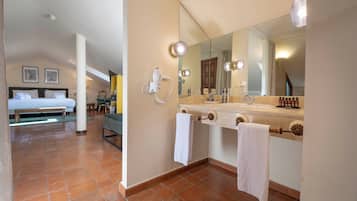A hotel room with a bed, a bathroom with a large mirror, a hairdryer, and a towel rack.