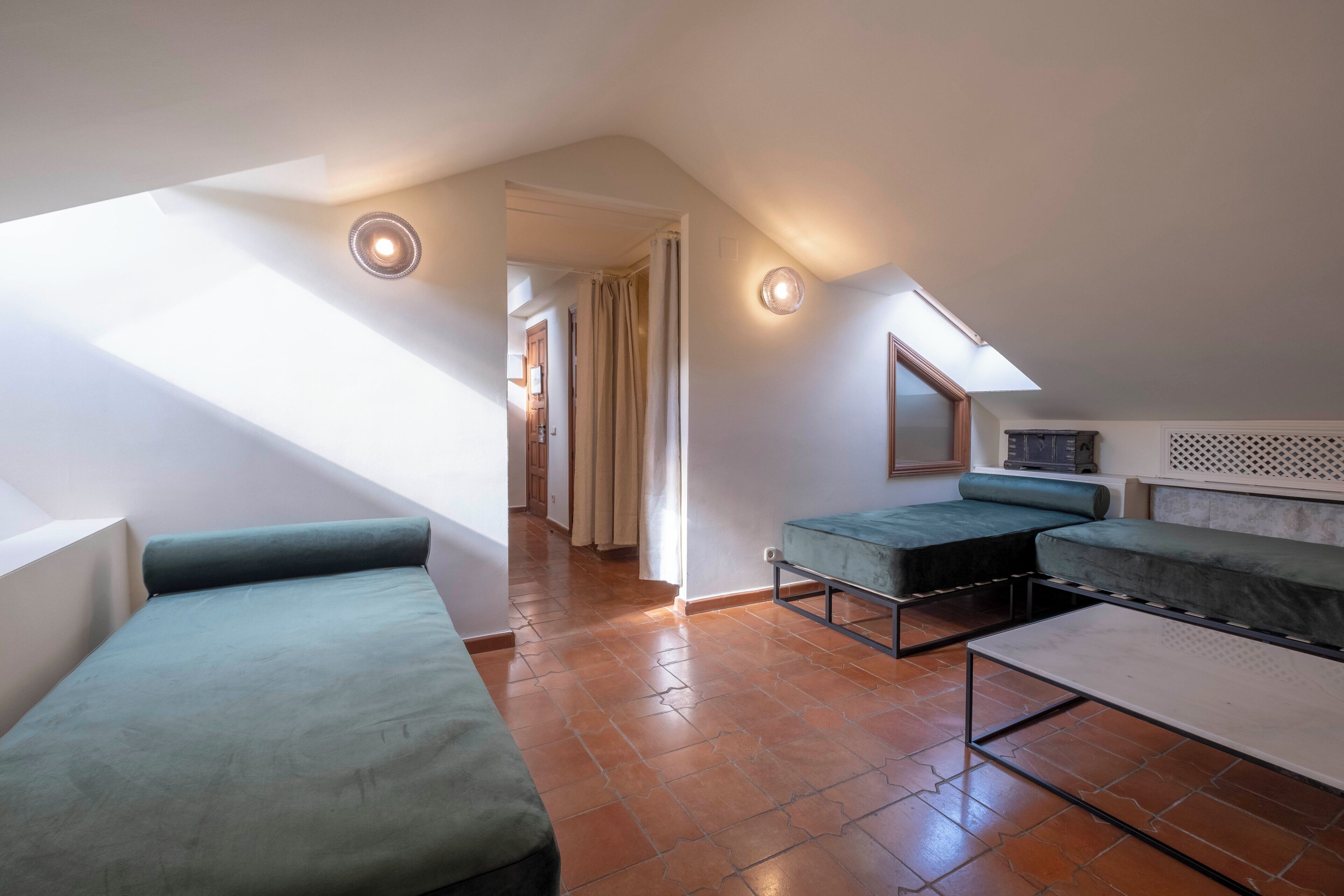 Un dormitorio tipo loft moderno con techo inclinado, asientos integrados y tragaluz.