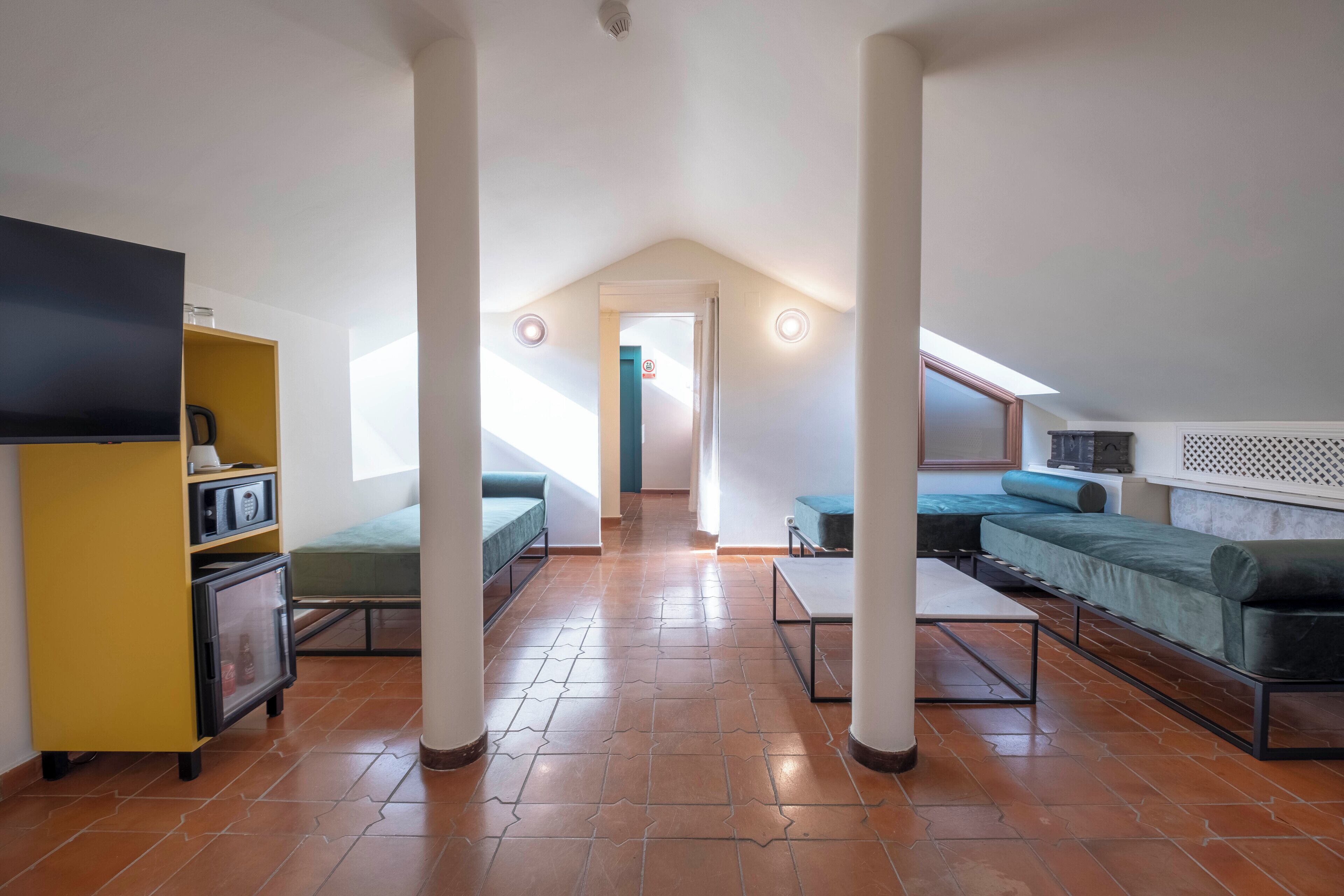 Un appartement-loft spacieux avec un plafond haut, une grande fenêtre, un canapé, un téléviseur et un petit coin cuisine.