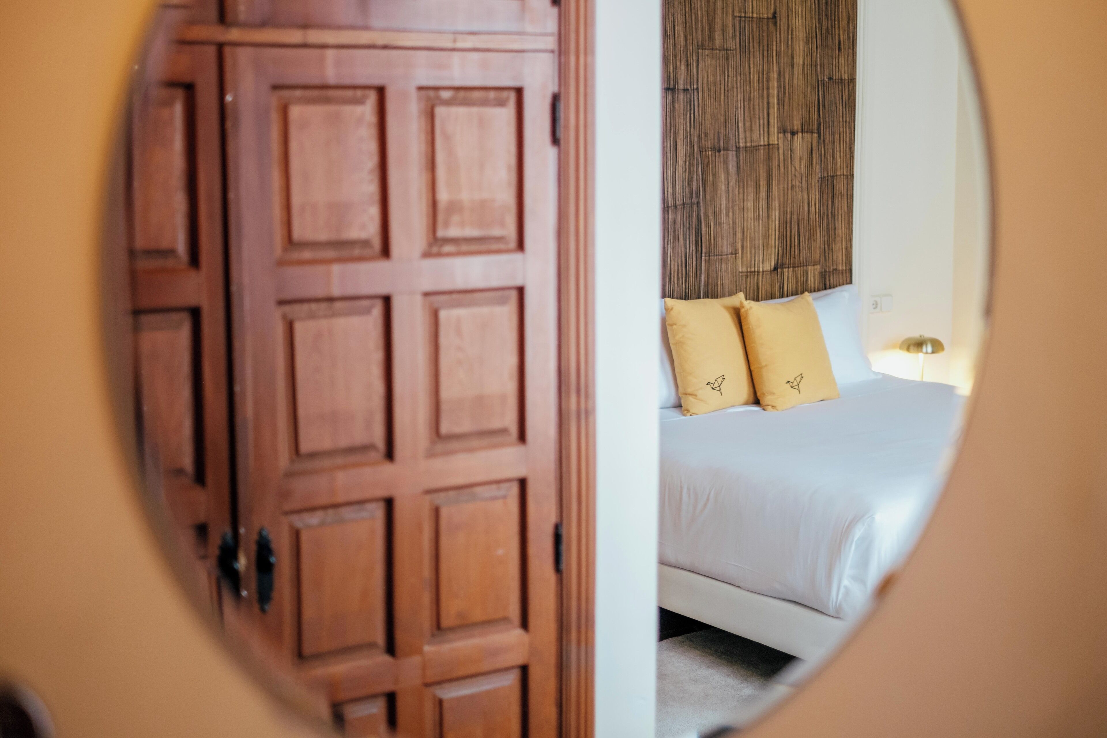 A bedroom with a bed, pillows, and a wooden door.