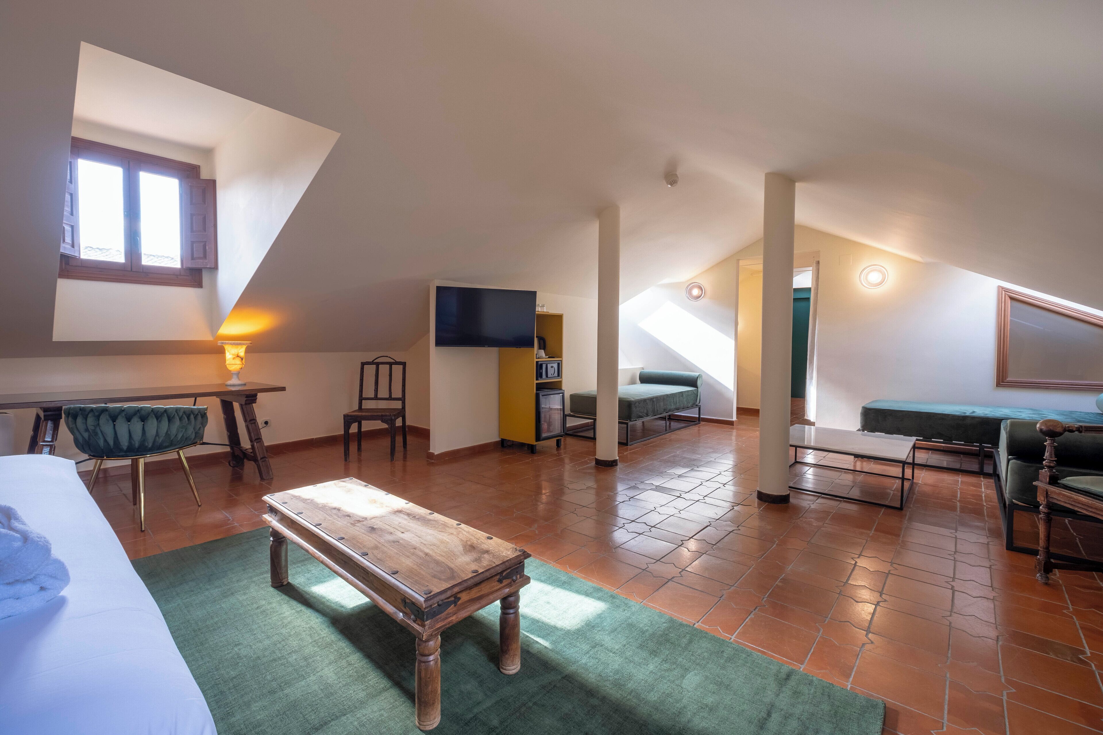Amplio dormitorio tipo loft con una cama grande, una mesa de madera, un escritorio y un televisor.