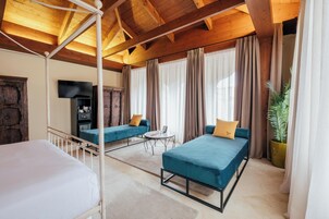 Ein Zimmer mit einem Bett, zwei Sofas, einem Fernseher und einer Pflanze.