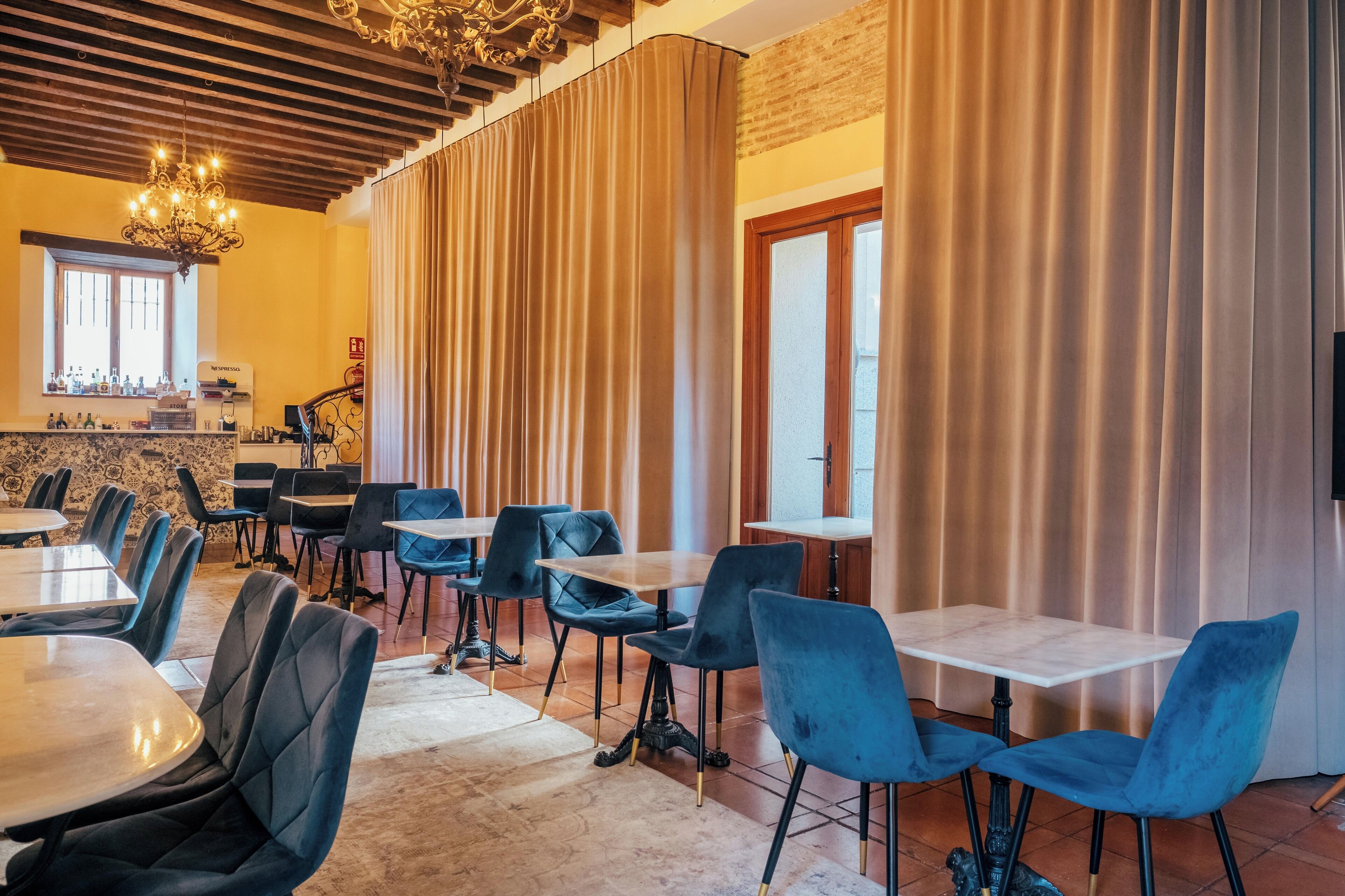 A dining area with tables and chairs, a chandelier, and a brick wall.