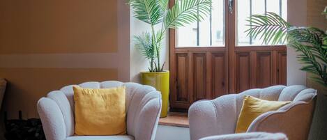 A cozy seating area with two armchairs and a small table, a potted plant, and a wooden door with a window.