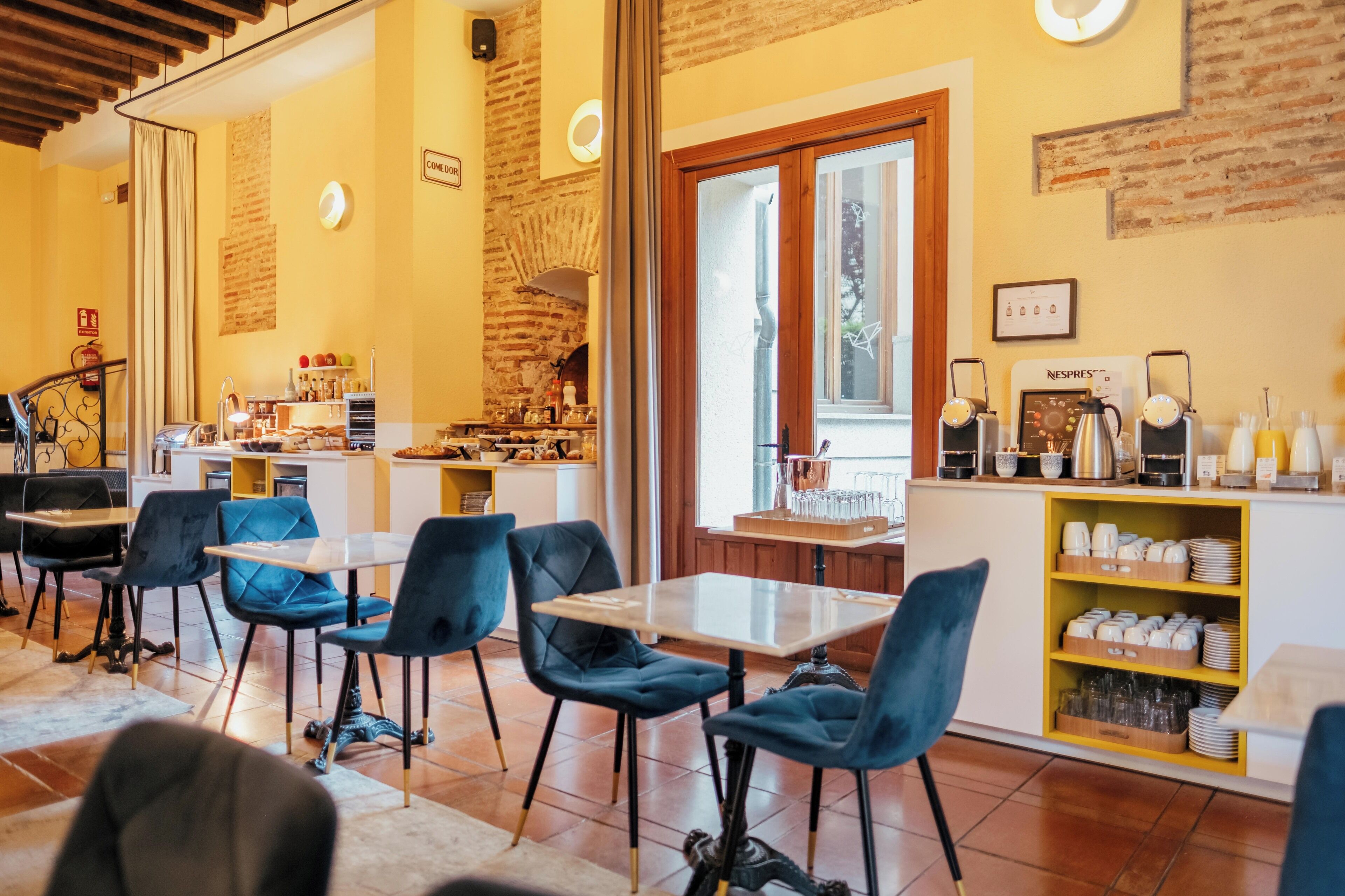 A café with blue chairs, a coffee bar, and a brick wall.