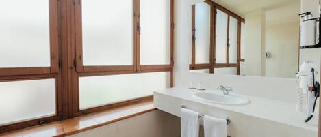 Un baño moderno con un amplio ventanal, un lavabo, un espejo y un perchero para toallas.