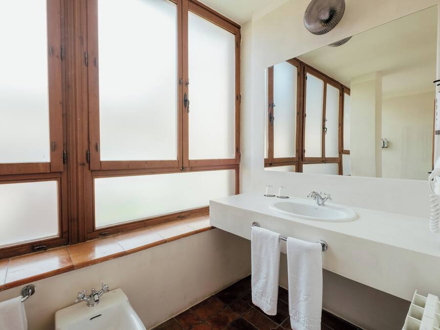 Un baño moderno con un amplio ventanal, un lavabo, un espejo y un perchero para toallas.