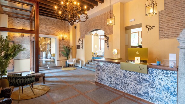 A lobby with a reception desk, patterned tiles, a chandelier, and a staircase leading to another area. - Hotel Cetina Palacio Ayala Berganza. (Segovia)
