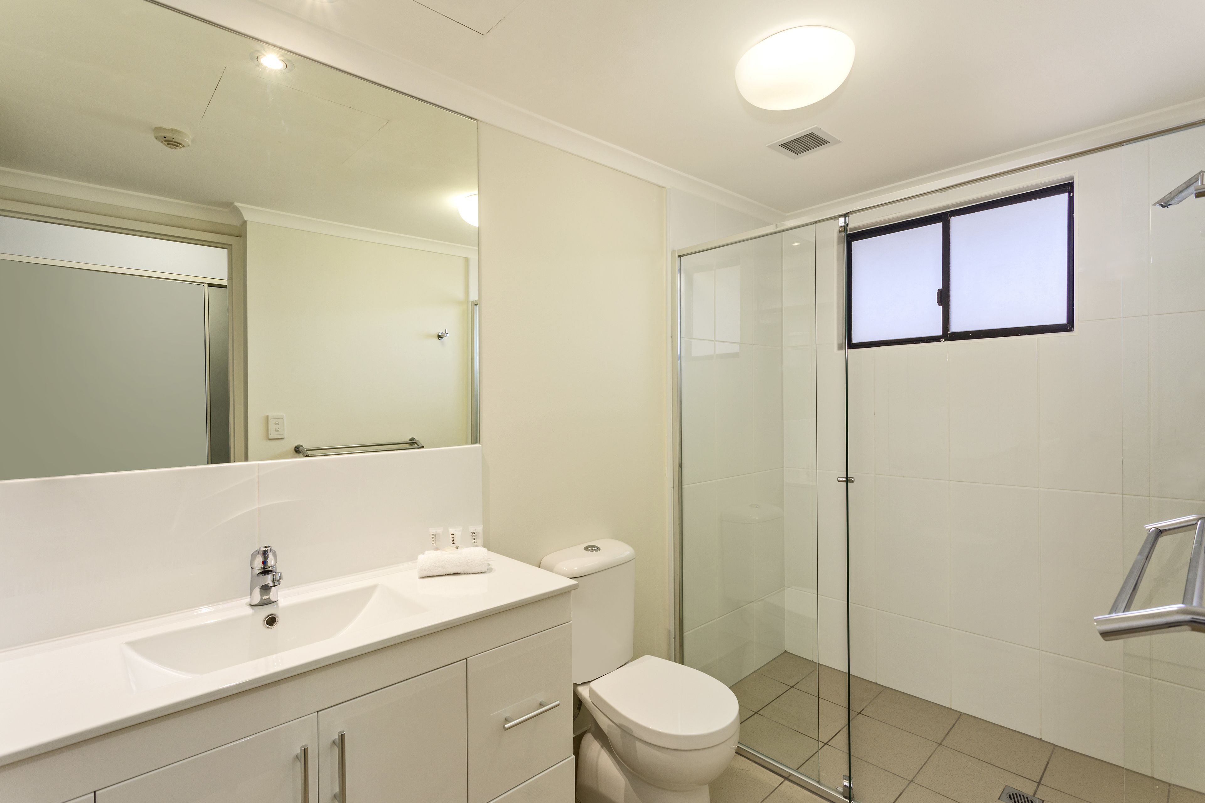 Een moderne badkamer met een douchecabine van glas, een witte wastafel en een toilet.