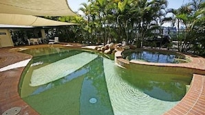 A swimming pool with a brick border and a canopy overhead.