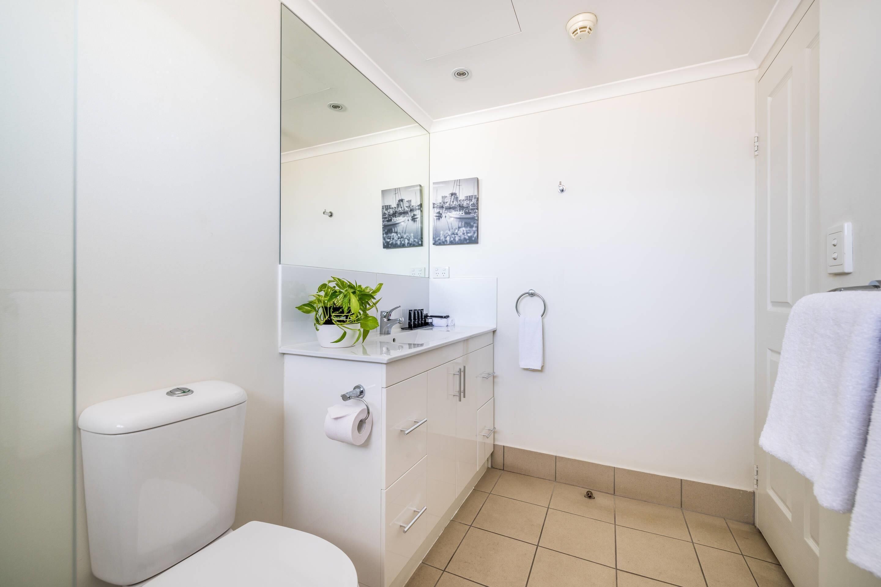 A modern bathroom with a toilet, sink, and mirror. There are two framed pictures on the wall.