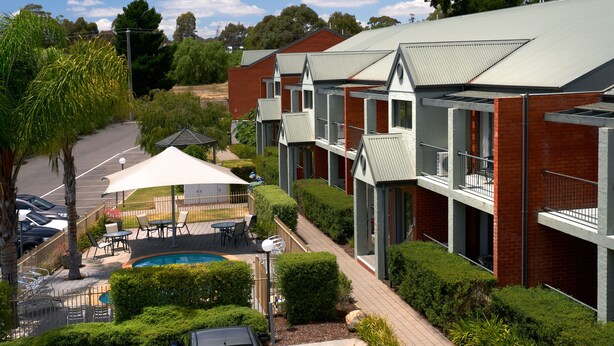 A modern building with multiple balconies, a swimming pool, and outdoor seating. - Quest Bendigo (Golden Square)