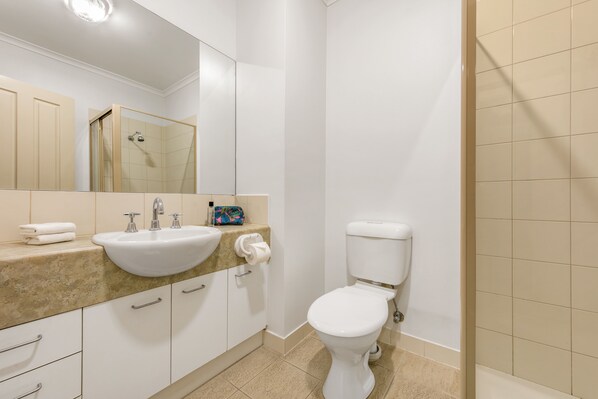 A modern bathroom with a white sink, mirror, and toilet.