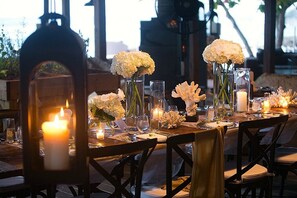 Una tavola imbandita per la cena, con candele, vasi di fiori e bicchieri.