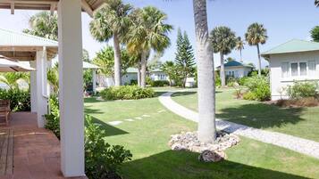 A resort with a covered patio area, palm trees, and a well-maintained lawn.