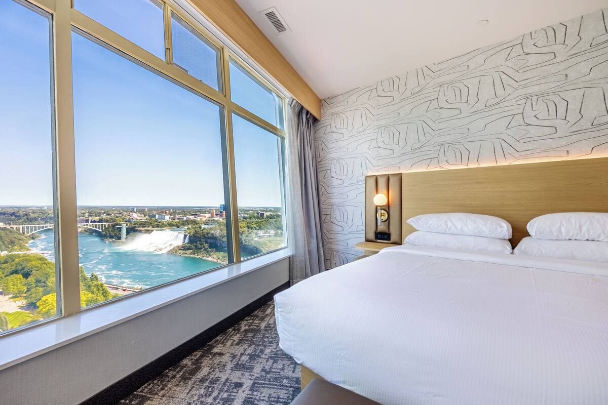 A hotel room with a large window offering a view of a bridge and water.