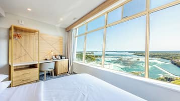 Una habitación de hotel con un ventanal grande, una cama, un escritorio y un armario.