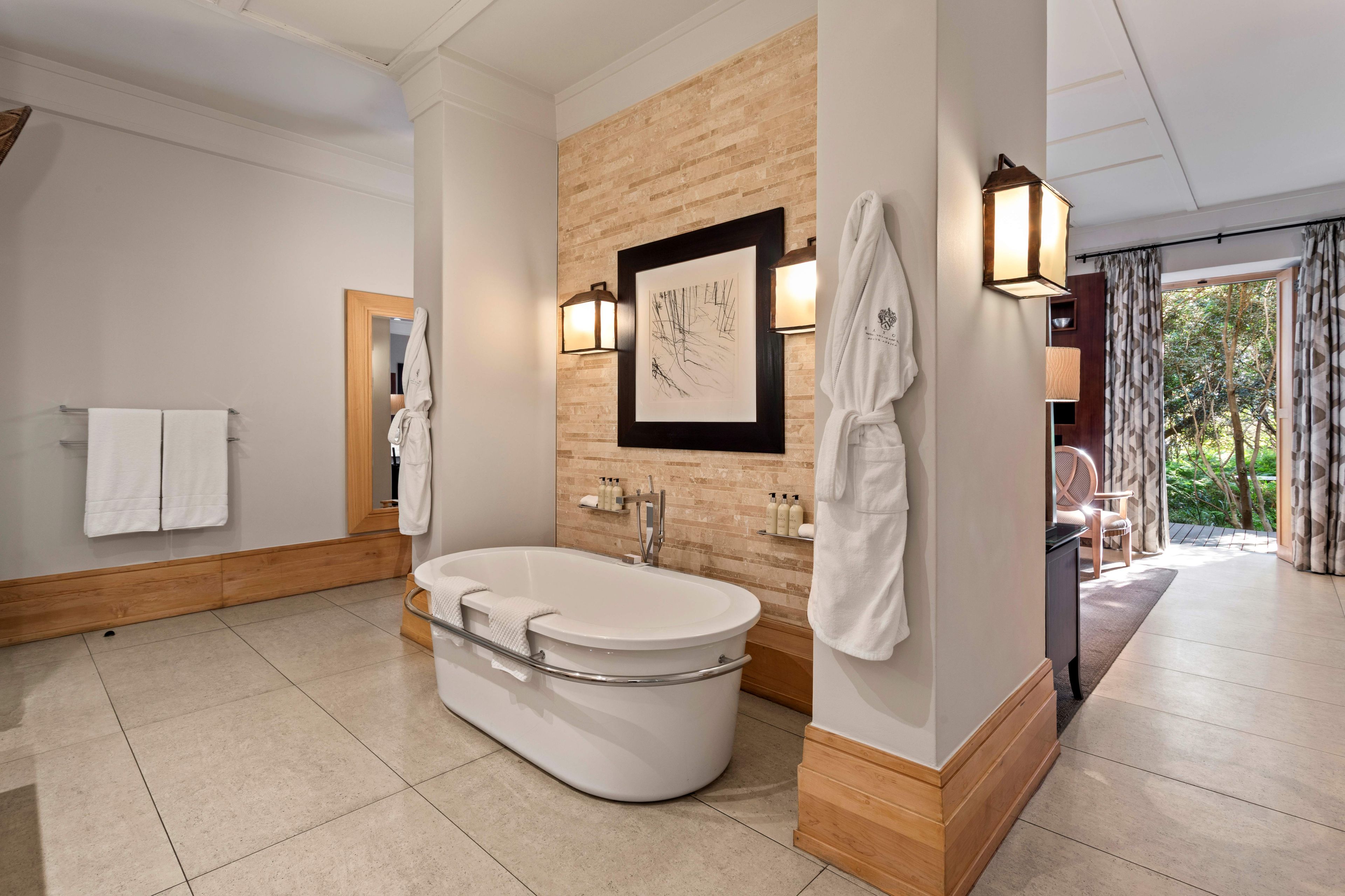 Un baño moderno con una bañera independiente, una pared decorativa de madera y una obra de arte enmarcada.