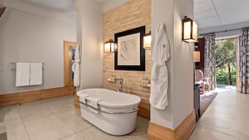 Un baño moderno con una bañera independiente, una pared decorativa de madera y una obra de arte enmarcada.