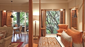 A bedroom with a large window, a bed with patterned bedding, a chair, and a table with chairs. - Saxon Hotel, Villas and Spa (Sandton)