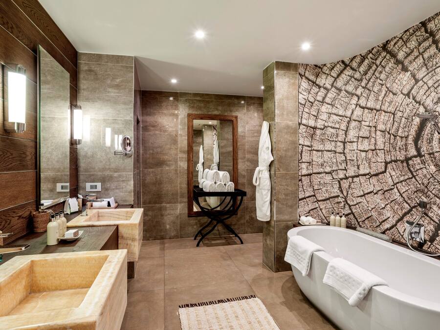Une salle de bain moderne avec une baignoire sur pieds, un meuble-lavabo avec un miroir et un grand miroir fixé au mur.