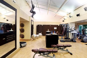 Ein Fitnessraum mit Trainingsgeräten, einem Spiegel und einer Rezeption.