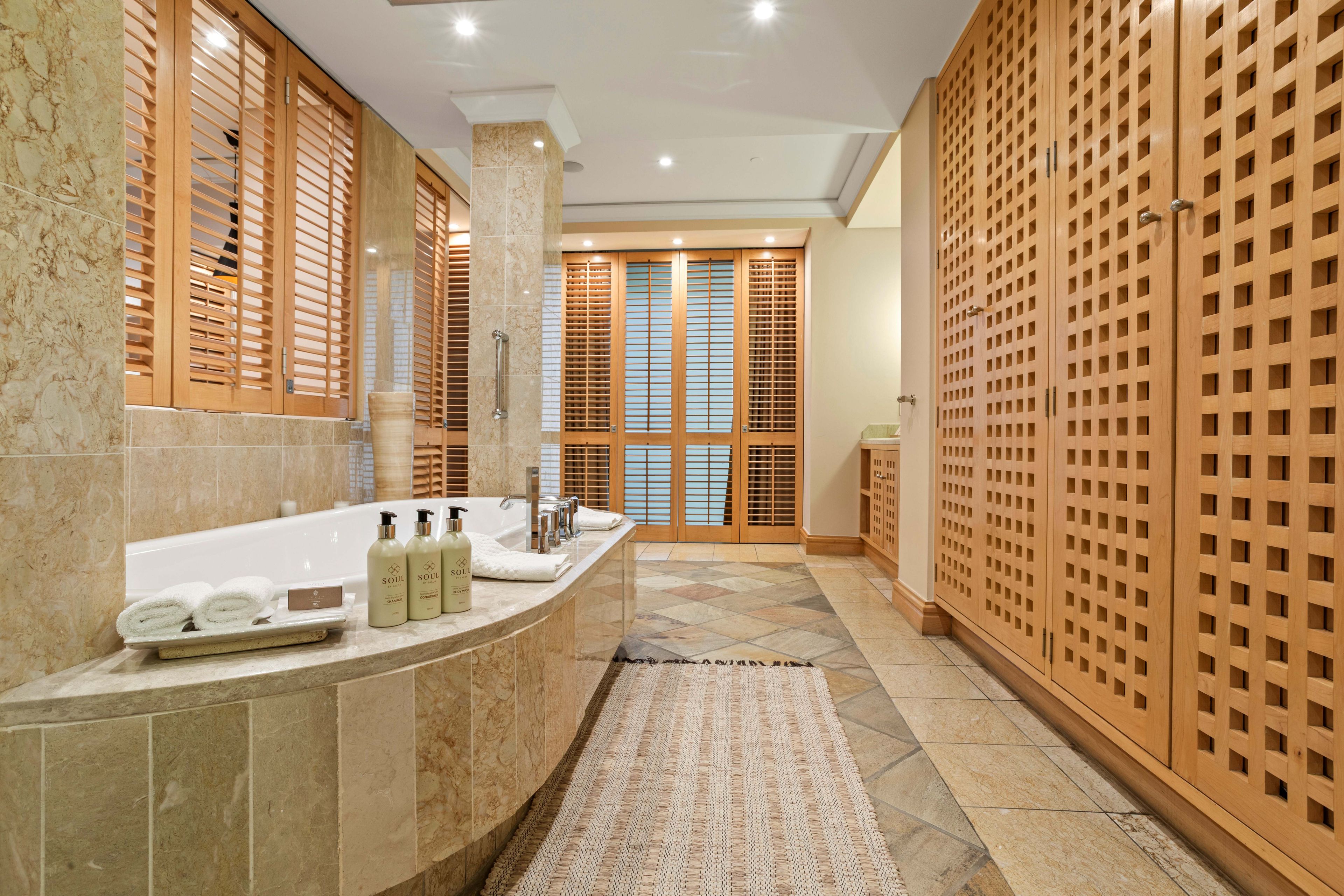 A modern bathroom with a curved sink, a large mirror, and wooden sliding doors.