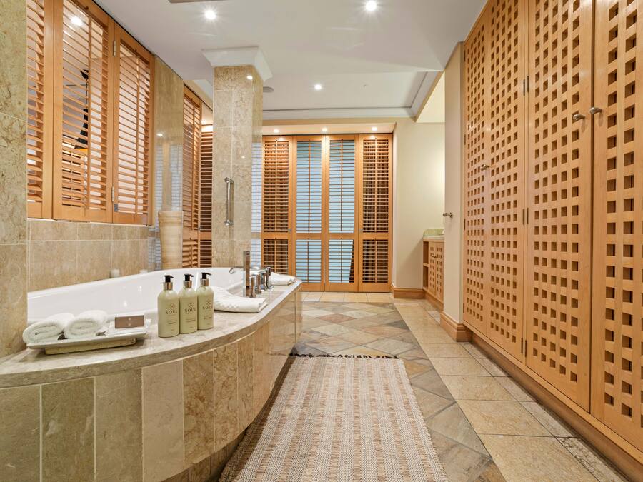 A modern bathroom with a curved sink, a large mirror, and wooden sliding doors.