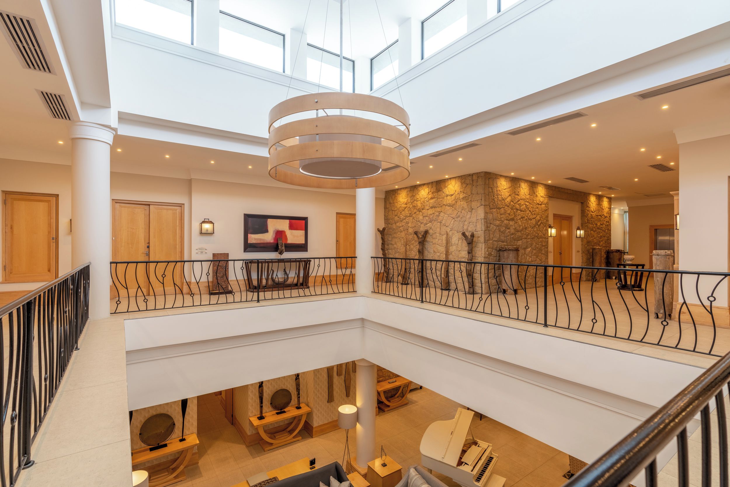 A multi-level hotel lobby with a grand staircase, a stone accent wall, and a piano.
