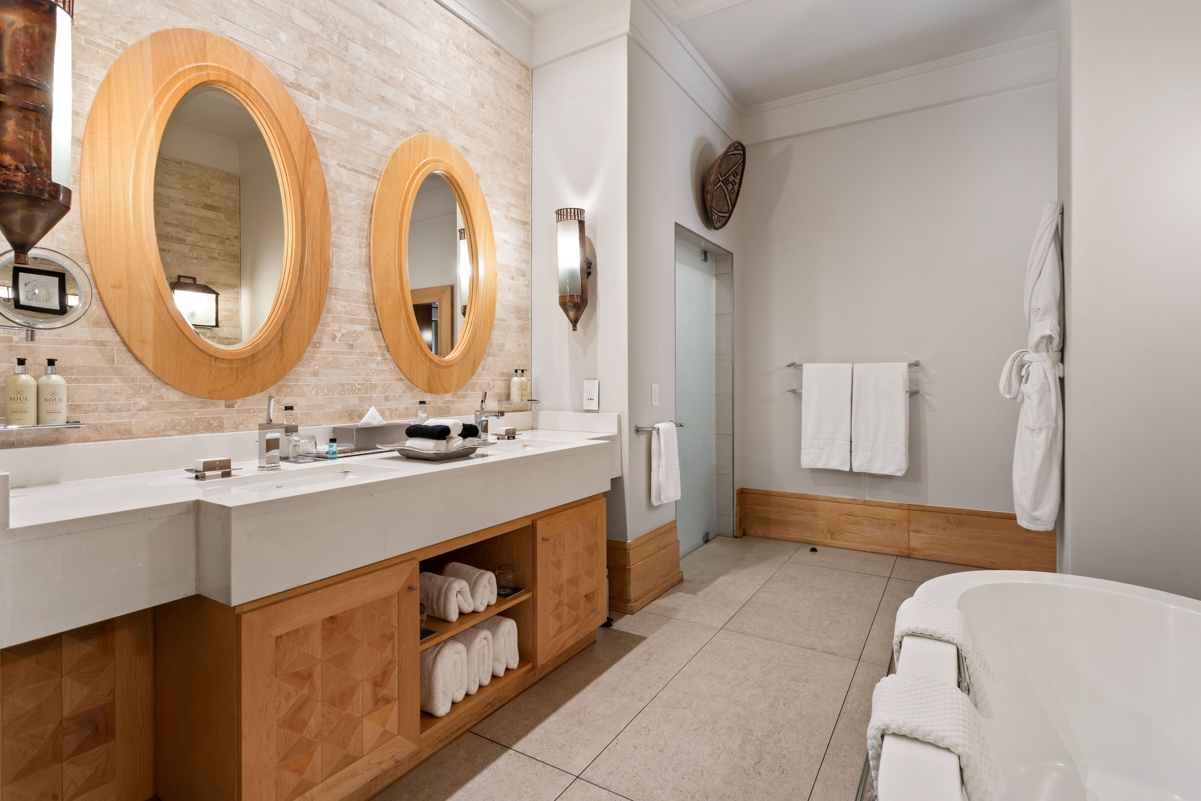 Un baño moderno con dos espejos grandes, un lavamanos blanco y una bañera.