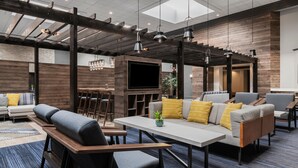 A modern lounge area with a sofa, chairs, a table, and a TV. - Marriott North Austin Round Rock (Round Rock)