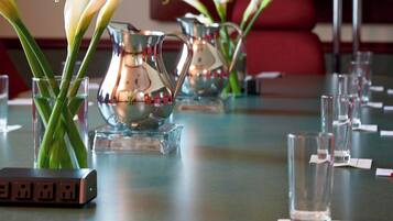 A table set with clear glassware, a silver pitcher, and a vase with white flowers.