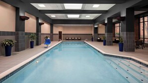 An indoor swimming pool with a tiled floor, seating area with chairs, and potted plants. - Marriott North Austin Round Rock (Round Rock)