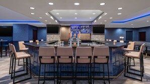 A bar area with a central island, bar stools, and a well-lit ceiling with recessed lighting. - Marriott North Austin Round Rock (Round Rock)