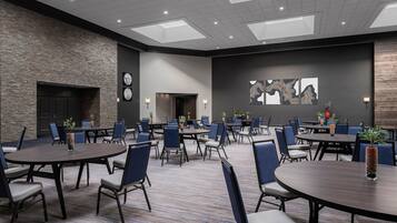 A conference room with multiple tables and chairs, a stone wall, a fireplace, and artwork on the wall.